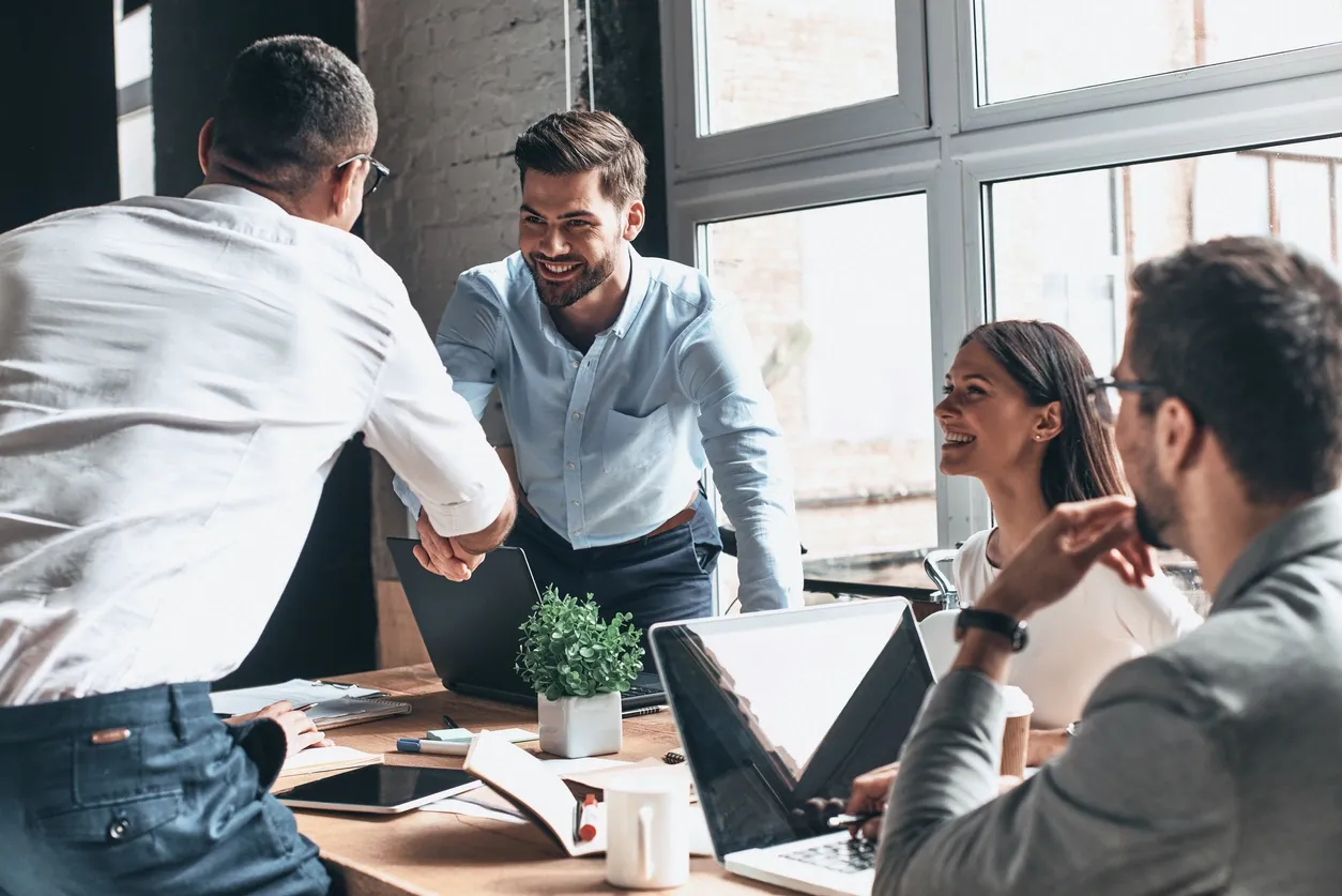 Business professionals shaking hands during a meeting in a bright office.