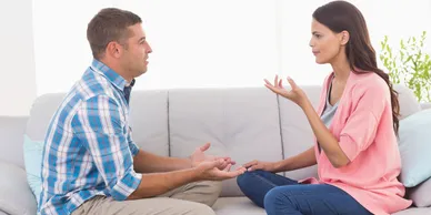 A couple engaged in a serious conversation on a couch.